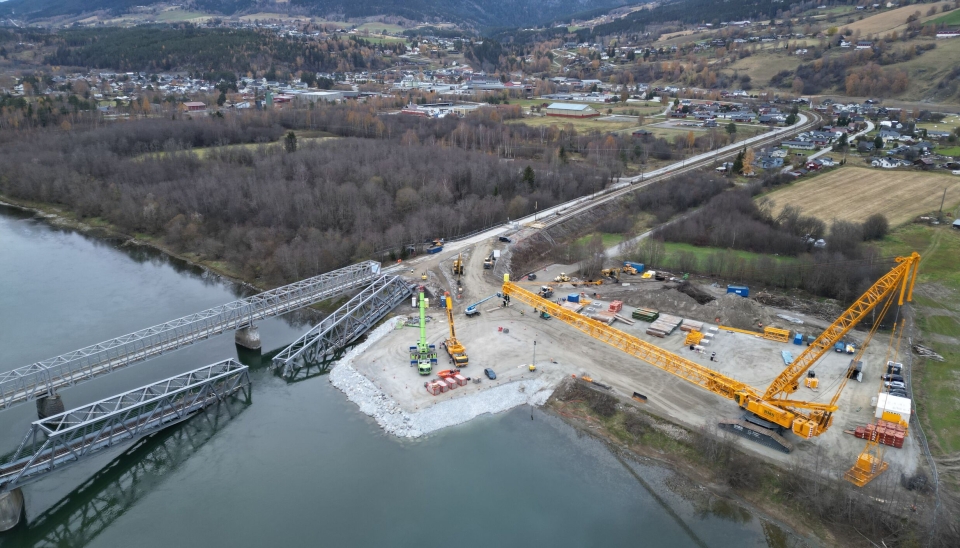 STOR KRAN: Når man ser de to mobilkranene på bildet, ser man hvor store dimensjoner det er på den beltegående fagverkskrana Liebherr LR11350 som skal løfte de to bruelementene fra elva og legge dem på land.